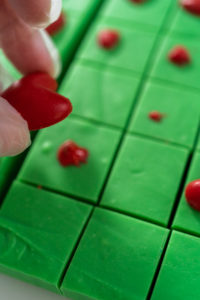 Decorating green fudge square pieces with chocolate red hearts.