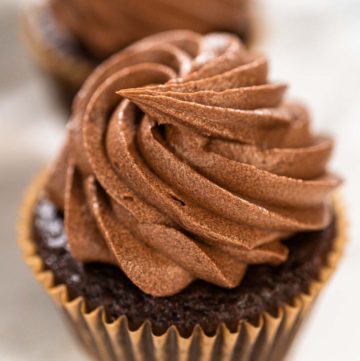 Baking Chocolate Cupcakes with Decadent Chocolate Frosting - Arina Photography Close-up of single chocolate cupcake topped with a perfect swirl of piped frosting.