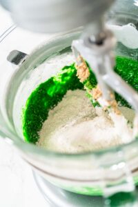 Vibrant Green Gingerbread Cookies for Festive Baking - Arina Photography Dry ingredients added to the green mixture in the mixer to complete the dough for Vibrant Green Gingerbread Cookies for Festive Baking. The flour, spices, and green blend create a festive dough.