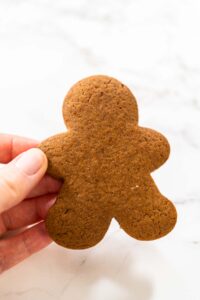 Step-by-Step Process of Making Spiced Gingerbread Cookies - Arina Photography Close-up view of a hand holding a Spiced Gingerbread Cookie, highlighting its festive holiday design and even baking.