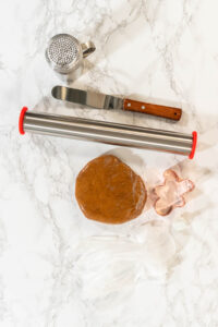 Preparing and Baking Classic Gingerbread Cookies in Gingerbread - Arina Photography A ball of gingerbread dough for Classic Gingerbread Cookies rests on a marble surface next to a rolling pin and gingerbread man cookie cutter, captured from an overhead angle.