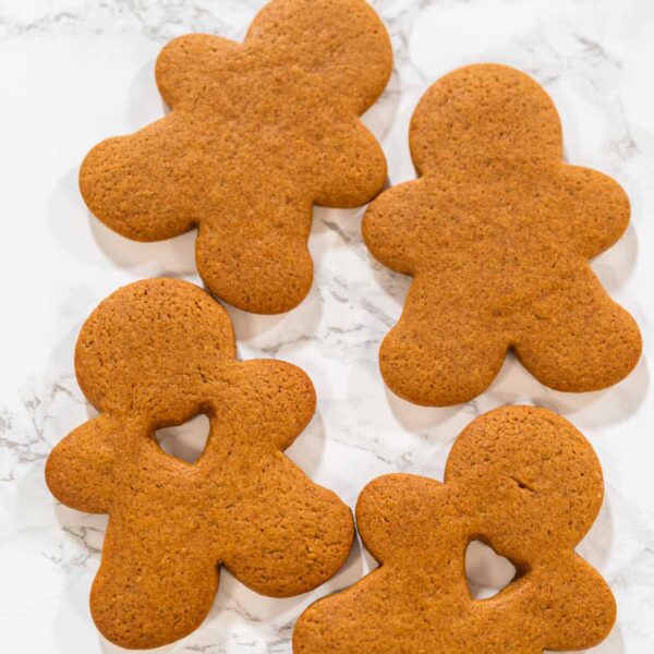 Preparing and Baking Classic Gingerbread Cookies in Gingerbread - Arina Photography A hand holding a gingerbread man cookie with a heart-shaped cutout, close-up view.