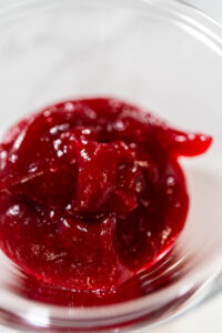 835-04947 - Arina Photography Close-up of smooth and glossy homemade cranberry puree in a glass bowl, ready to use for baking or frosting.