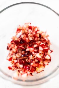 835-04988 - Arina Photography Close-up of finely diced fresh cranberries in a glass bowl, showing their bright red skins and pale interiors.
