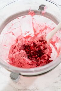 835-05196 - Arina Photography Pink cranberry buttercream being whipped in a glass bowl with chopped cranberries ready to fold in.