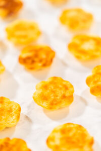 835-05261 - Arina Photography Baked lemon spritz cookies placed upside down on parchment paper, showing their golden browned bottoms.