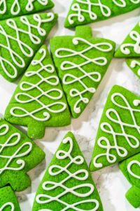 Decorating Festive Christmas Tree Cookies with Royal Icing - Arina Photography Green Christmas tree cookies decorated with white royal icing in swirl patterns, perfect for holiday baking and cookie boxes.