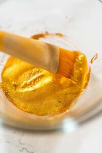Perfectly Icing Star Cookies with Royal Icing - Arina Photography Close-up of a food-safe brush dipped in shimmering edible gold luster dust, mixed with clear vanilla extract—ready for painting cookies with a festive metallic finish.